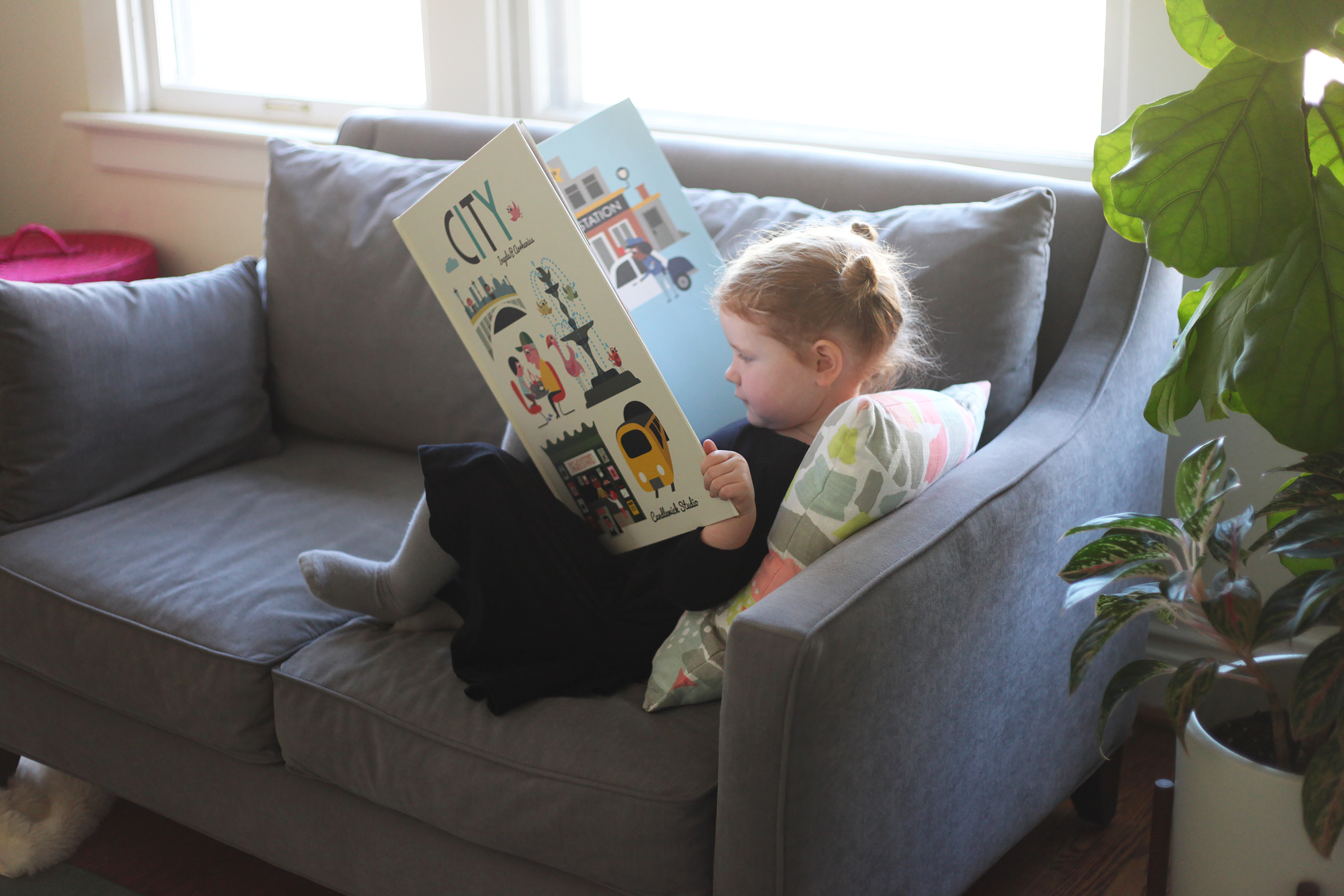 Child-Reading-Oversize-Book-On-Couch